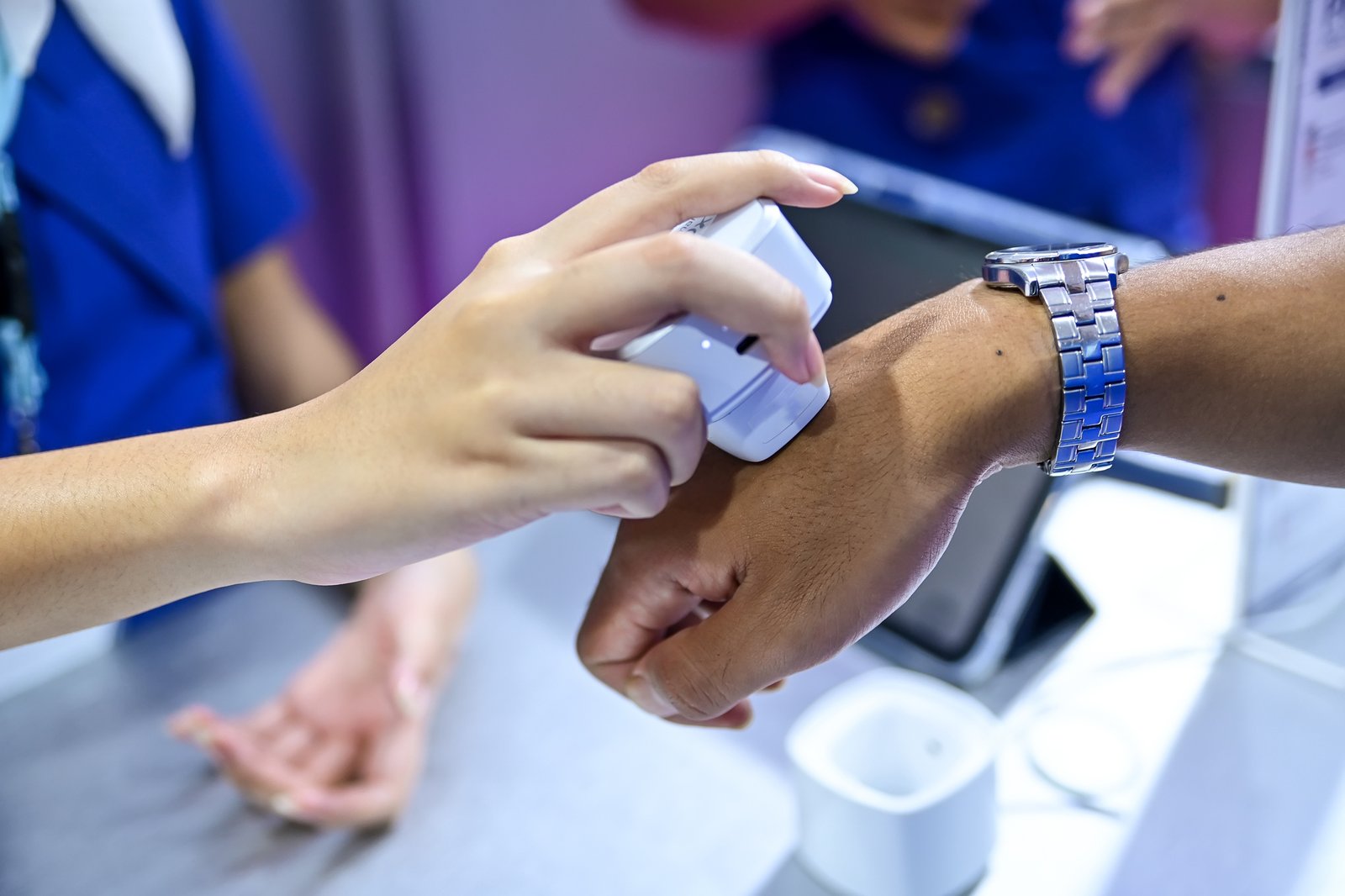 close up shot showing a hand held electronic device being pressed against a person's wrist for a medical or cosmetic scan